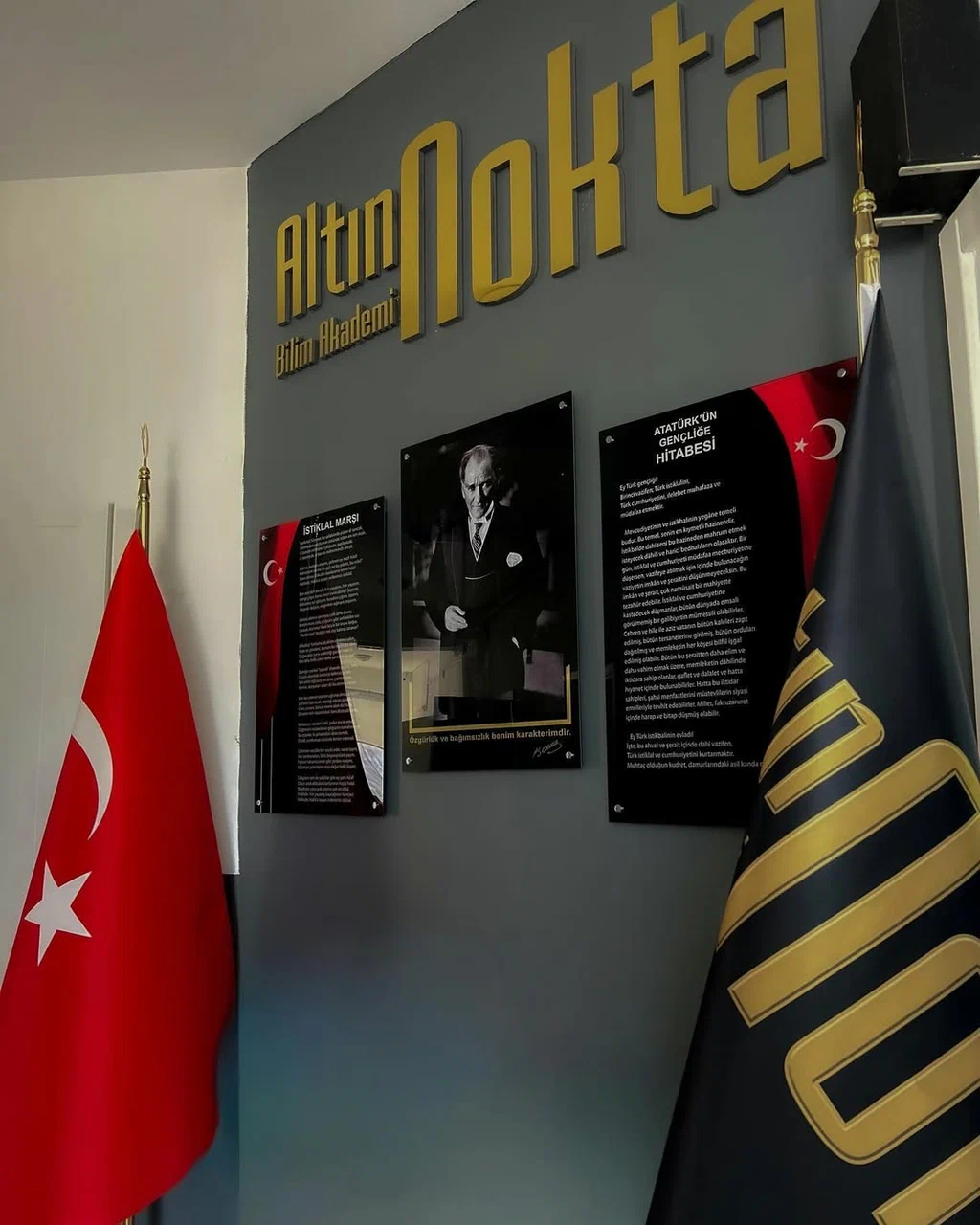 Altın Nokta Bilim Akademi'nin iç mekânı — duvarda altın renkli logo, Türk bayrağı ve Atatürk köşesi